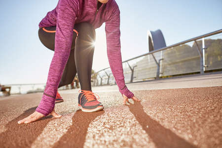 Ready to go. Cropped shot of active mature woman wearing sportswear standing in start position, ready for running outdoors on a sunny dayの写真素材