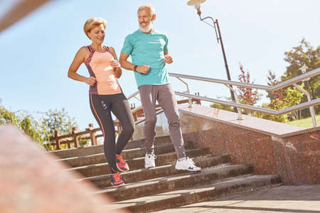 Healthier and Happier. Full length shot of active mature family couple in sportswear looking happy while jogging together on a warm sunny day. Joyful senior couple doing sport outdoorsの写真素材