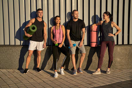 Happy two men and women going to train together in the cityの写真素材