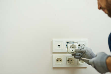Close up shot of hands of electrician wearing protective gloves installing new socket in a houseの写真素材