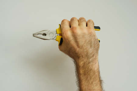 Hand of repairman holding hand tool, pliers over white backgroundの写真素材