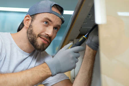 Dedicated to excellence. Close up portrait of young repairman, professional plumber looking cheerful...
