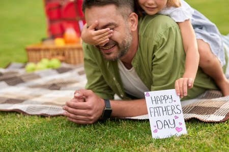 Cute little girl surprising her father, greeting and giving him handmade postcard, daddy and daughter celebrating Fathers Day in the parkの写真素材