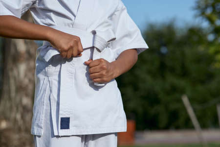 Afro American tittle girl tying belt on karate kimonoの写真素材