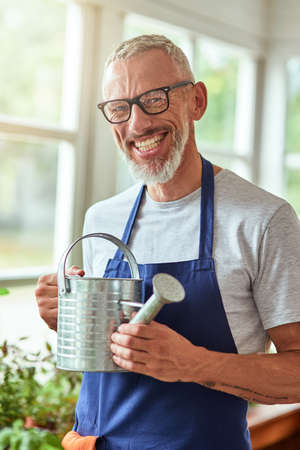 Middle aged caucasian man holding watering canの写真素材