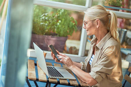 Middle aged caucasian woman dialing number on phoneの写真素材