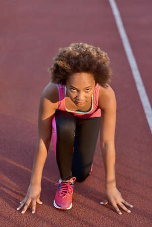 Sporty little girl standing in start position before the sprint