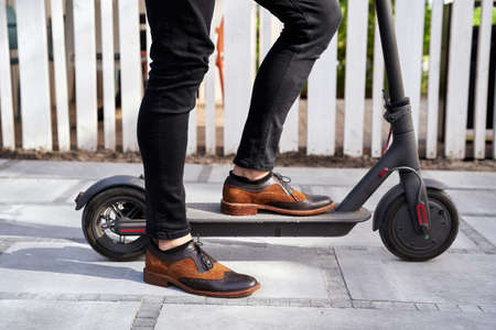 Get there. Close up shot of stylish mature businessman standing with his electrical scooter outdoorsの写真素材