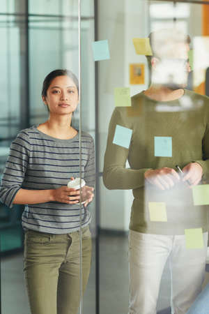 Two office colleagues putting reminders on the wall