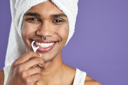 Transgender man with floss smile on isolated purple background headshot portraitの写真素材