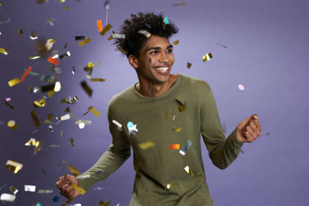Joyful african american young man dancing with gold confetti portrait. Laugh and smiling transgenderの写真素材