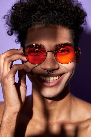Close up verticale portrait of latino male in orange glasses. Cheerful transgender model perfect bodyの写真素材