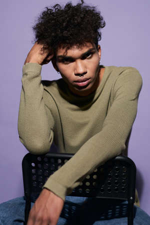 Close-up portrait of afroamerican male looking camera on purple background. Young transgender manの写真素材