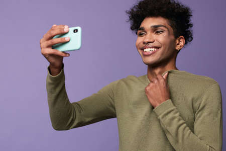 Portrait of transgender latino male taking selfies with mobile in hand. Happy trans gender young manの写真素材