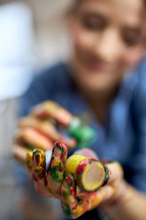 Close up shot of female artist holding colorful acrylic oil paints in jarsの写真素材