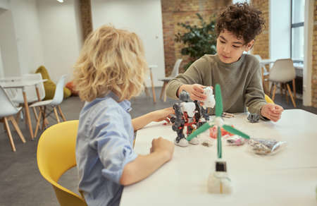 Busy little boys examining robots, sitting at the table during STEM classの写真素材