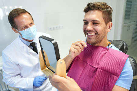 Young man trying enamel samples from teeth whitening kitの写真素材