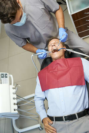 Qualified dentist monitoring teeth of his male patientの写真素材