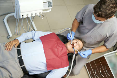 Young dentist doing regular medical check-up of patient teethの写真素材