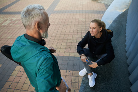 High angle view of sportive mature couple, man and woman in sportswear talking outdoors while waiting together for workoutの写真素材