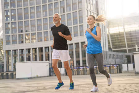 Active middle aged couple, man and woman jogging together in the morning while training outdoorsの写真素材