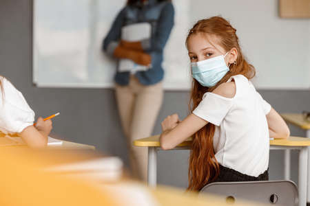 Cute girl sitting at her desk at school