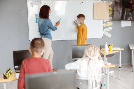 Teacher and schoolboy standing near the blackboard in the classroomの写真素材