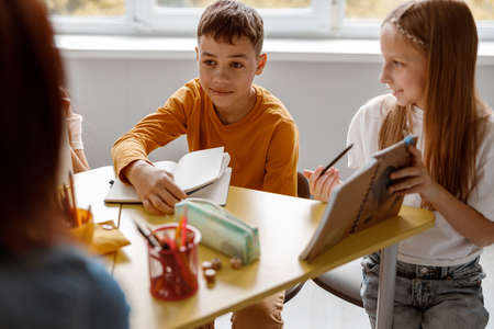 Smiling kids sitting at the table and using notebooksの写真素材