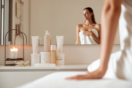 Charming woman sitting near cosmetic products in spa salonの写真素材