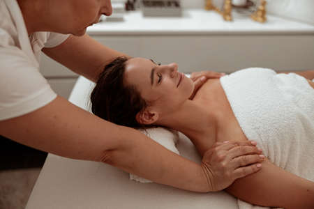 Smiling young woman receiving professional massage in spa salonの写真素材