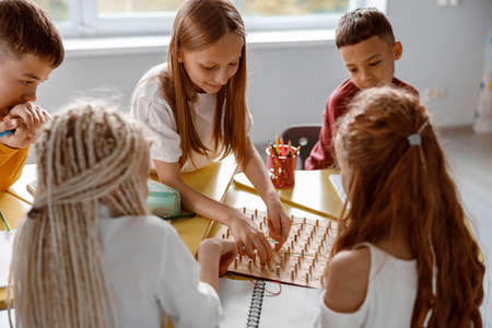 Smiling schoolchildren using geoboard in classroom togetherの写真素材