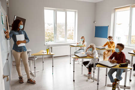 Female teacher holding notebook and marker in classの写真素材