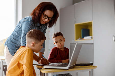 Afro American teacher in glasses and kids during lesson in classroomの写真素材