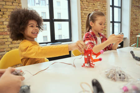 Problem solving. Curious little kids looking interested at technical toys while sitting at the table during STEM classの写真素材