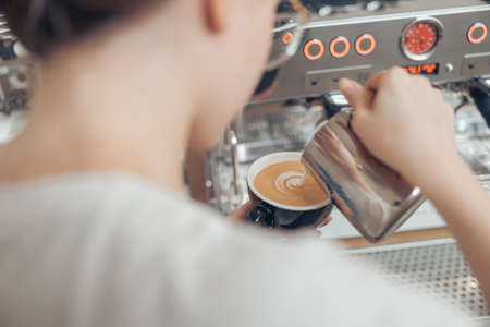Female barista making latte art in coffee shopの写真素材