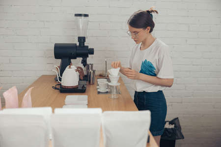 Charming young woman making coffee filter in cafeteriaの写真素材