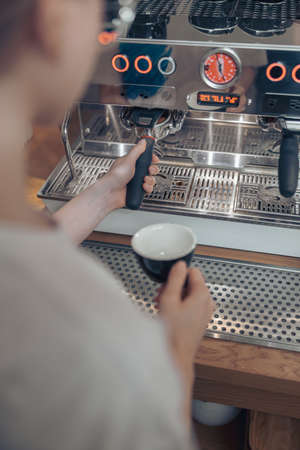 Young woman barista using professional coffee machine at workの写真素材