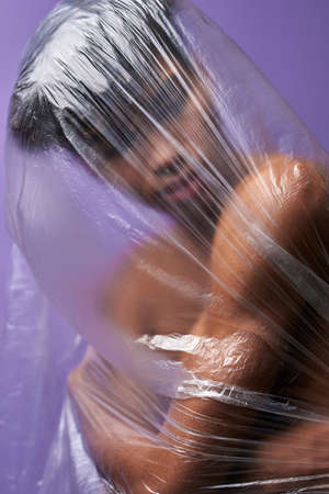 Portrait of young hispanic man with transparent plastic bag on body. Claustrophobia asphyxiationの写真素材