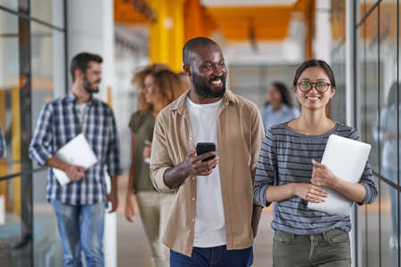 African man holding smartphone and speaking with womanの写真素材