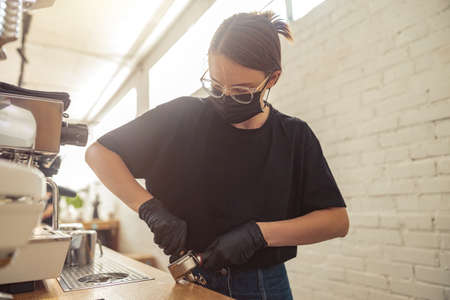 Woman in protective mask and gloves in cafeteriaの写真素材