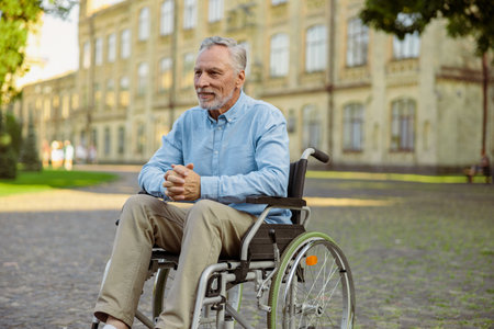 Pensive mature recovering man in wheelchair looking away while spending time alone in the park near hospitalの写真素材