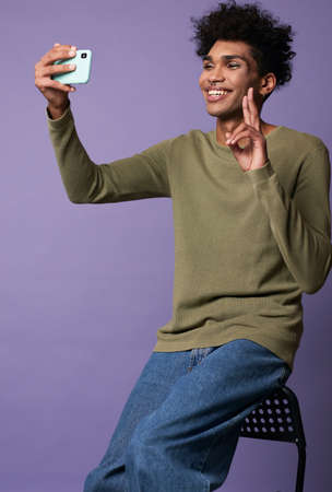 Portrait of cheerful transgender young man taking selfies with mobile phone in handの写真素材