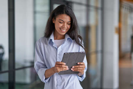 Happy woman working with modern gadget in officeの写真素材