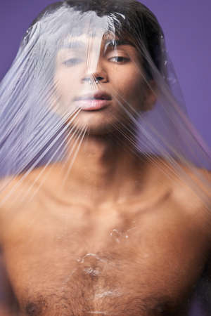 Transgender model with plastic bag on head portrait. Scared young man with claustrophobia problemの写真素材
