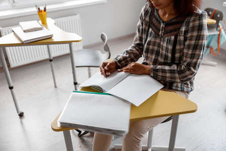 Teacher sitting at a desk and writing in a notebook