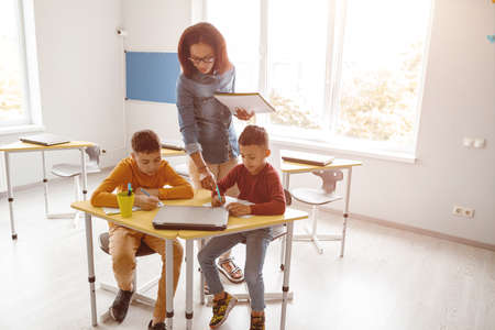 Two boys sitting and writing during a lesson at schoolの写真素材
