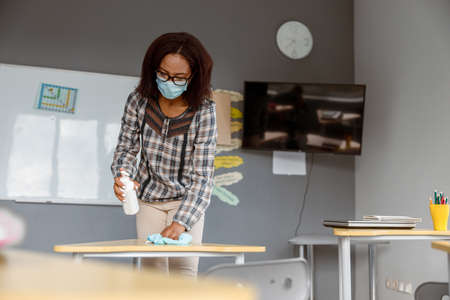 Teacher holding disinfectant and standing in classroomの写真素材