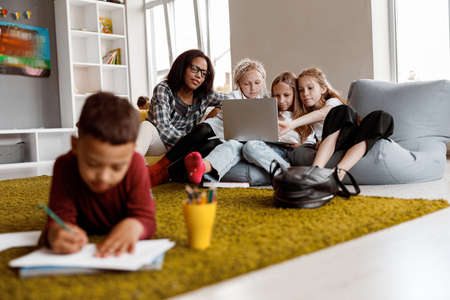 Teacher and girls working with laptop in classの写真素材