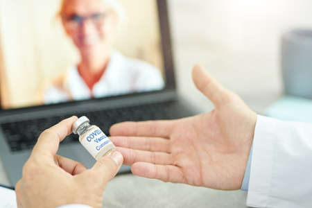 Male doctor discussing coronavirus vaccine with colleague virtuallyの写真素材