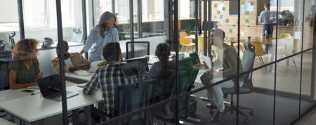 Group of happy smiling multiracial business people discussing project results, communicating while having a meeting in a conference or board room in the modern coworking spaceの写真素材